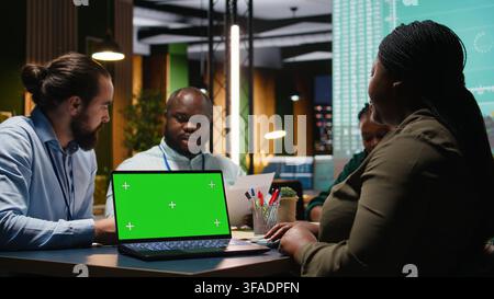 Diverse staff employees in a late meeting with isolated mockup, discussing about strategy with group of shareholders and team members. Setting goals for project agenda. Camera A. Stock Photo