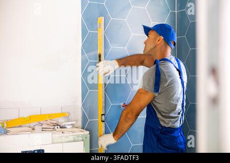 Repairer using spirit level on wall, working on home improvement Stock Photo