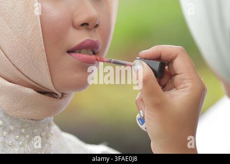 East Java,11/02/2019  Makeup Artist Applying Lipstick to Client's Lips Stock Photo