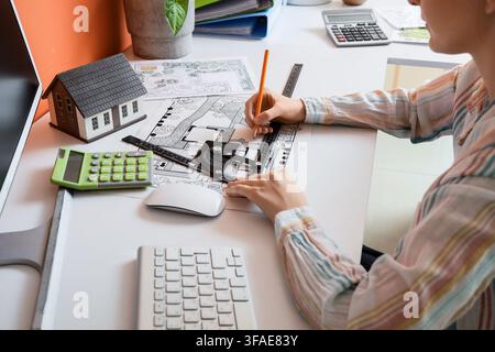 Home design and architecture planning, person drawing house plans with model house and calculator on a white desk Stock Photo