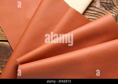 Leather craft and upholstery material, brown faux leather fabric samples on a rustic wooden background, textile industry Stock Photo