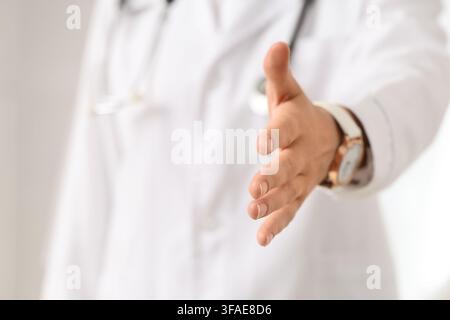 Healthcare partnership and medical collaboration, doctor offering handshake for trust and support in clinic Stock Photo