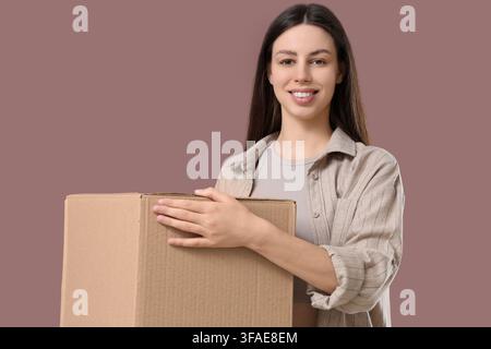 Delivery and shipping services, happy young woman holding a cardboard box for moving or online shopping Stock Photo