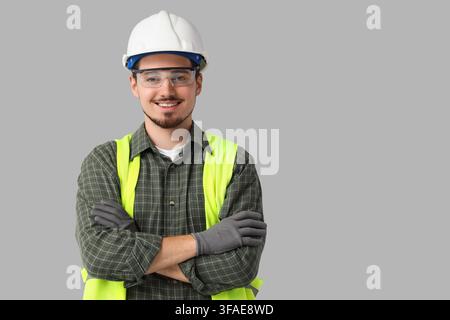 Construction worker safety and professional service, young man in hard hat and reflective vest with arms crossed Stock Photo