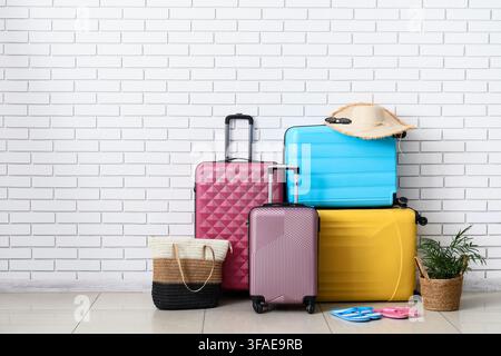 Travel and vacation planning, colorful luggage and beach accessories ready for summer holiday trip against a white brick wall Stock Photo