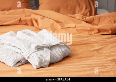 Folded waffle bathrobes on bed in room Stock Photo