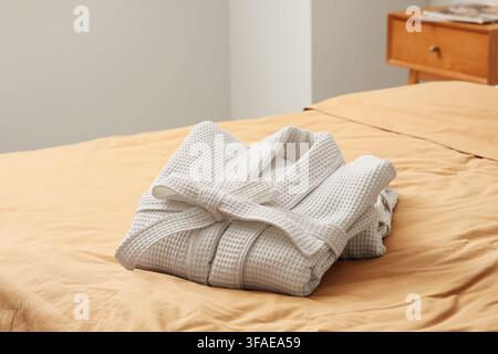 Folded waffle bathrobes on bed in room Stock Photo