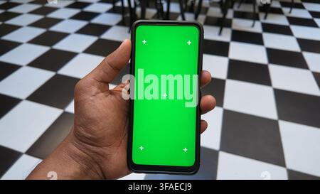 Hand holding a smartphone with a green screen display Stock Photo