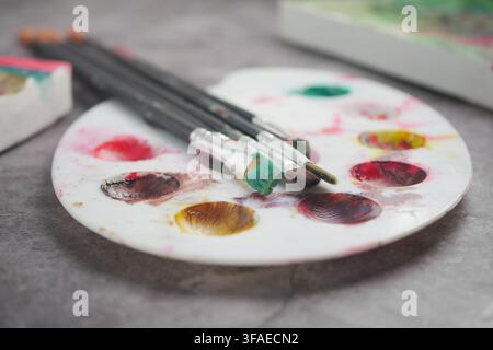Paint brushes and colors on a palette at an art table Stock Photo
