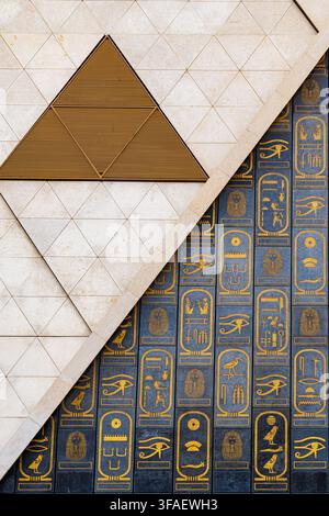 Close-up of the geometric stone facade and golden hieroglyphic panels on the exterior of the Grand Egyptian Museum in Giza, Egypt. Stock Photo