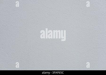 A smooth, light gray textured wall surface. The wall has a subtle, uniform appearance with no visible patterns or markings Stock Photo
