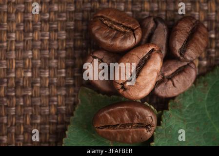 Roasted coffee beans on a textured burlap and dark wooden background. Stock Photo