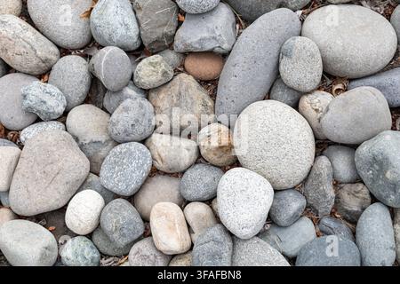 Close-up overhead view of assorted smooth rounded stones creating a neutral natural background and texture. Stock Photo