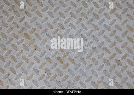 Close-up full-frame view of a weathered metal surface with a repeating raised anti-slip pattern. Stock Photo