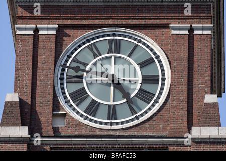 Close-up of a large traditional clock face set into the brick facade of a historic building in Seattle, Washington. Stock Photo