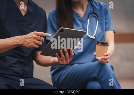 Medical team using digital tablet during coffee break time outdoors Stock Photo