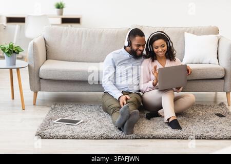 Black man and woman having videocall using laptop waving hand Stock Photo