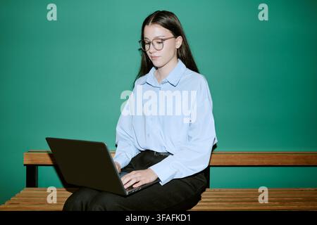 Female Student Using Laptop on Campus Bench for Online Learning Stock Photo