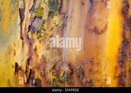 Close-up of rusted, peeling yellow paint on an old tractor used to launch boats on Aldeburgh beach, Suffolk, its weathered metal surface covered in pa Stock Photo