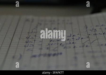 A blurred macro shot of handwritten calculus equations on a notebook page, with only a few lines in sharp focus. Stock Photo