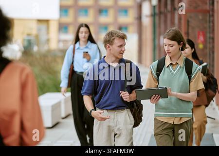 Diverse Students Walking on Campus and Using Digital Tablet Stock Photo