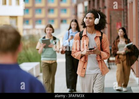 Diverse Students Walking on Campus and Using Smartphones Stock Photo