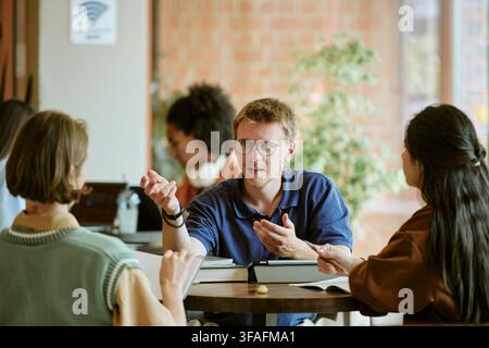 Diverse Students Studying and Discussing Project in Campus Cafe Stock Photo