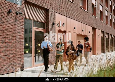 Diverse Group of Students Walking and Talking on University Campus Stock Photo