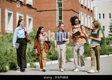 Diverse Multiethnic Students Discussing Homework While Walking on Campus Stock Photo
