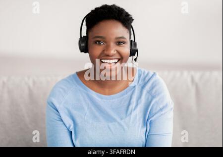 Black woman sitting, looking to camera wearing headset Stock Photo