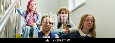 Portrait of Group of School Children Sitting on Stairs during Break Stock Photo