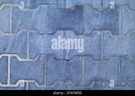 Gray Interlocking Concrete Paving Stones Pattern. Close-up top view of gray interlocking concrete paving stones forming a repeating geometric pattern Stock Photo