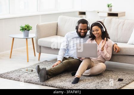 Black man and woman having videocall using laptop waving hands Stock Photo