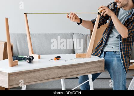 Mechanic assembled furniture in house according to manual, along with equipment, screwing screw, drilling holes Stock Photo