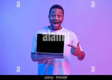 Check This. Overjoyed Black Guy Pointing At Laptop Computer With Blank Screen Stock Photo