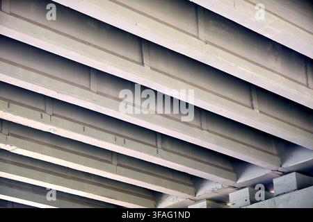 Concrete bridge underside featuring repeating diagonal beams, solid architectural structures, industrial infrastructure support, grey cement perspecti Stock Photo