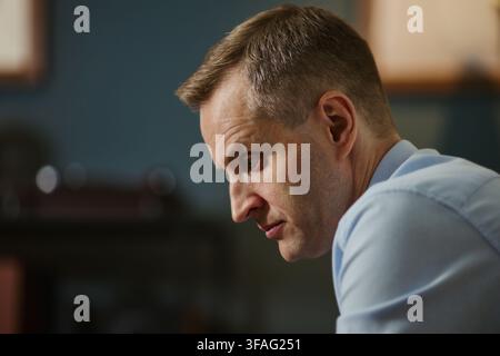 Middle aged Caucasian businessman looking down with serious expression, representing stress, burnout, or deep concentration. Ideal for corporate mental health campaigns, close up Stock Photo