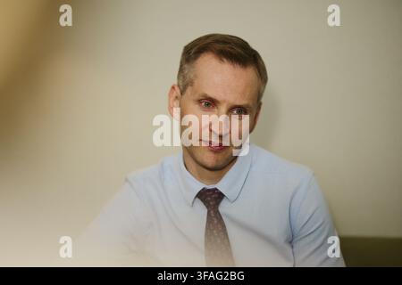 Middle aged Caucasian businessman looking away thoughtfully during corporate meeting. Image represents professional leadership and decision making in business marketing Stock Photo