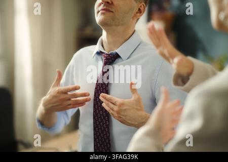 Middle aged Caucasian businessman using sign language to communicate with colleague in office. Image represents diversity and inclusion in corporate communication, close up Stock Photo