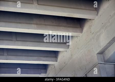 Concrete bridge underside featuring repeating diagonal beams, solid architectural structures, industrial infrastructure support, grey cement perspecti Stock Photo