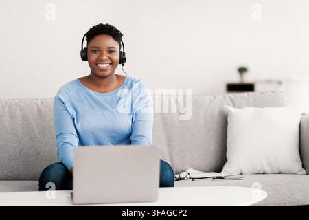 Black woman sitting, looking to camera wearing headset Stock Photo