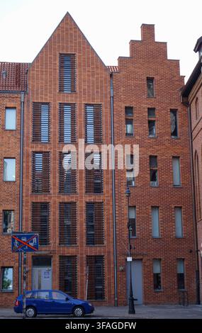 Facade of modern red brick apartment building with integrated wooden shutters and a gabled roof. Stock Photo