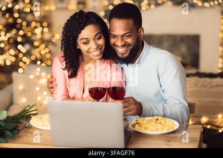 Black couple having videocall using laptop drinking wine Stock Photo