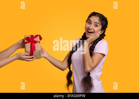 Female hands holding and giving present box to indian woman Stock Photo