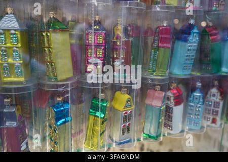 Glass Christmas tree ornaments shaped like historic townhouses displayed in clear plastic tubes inside a souvenir window store front, sparkling. Stock Photo