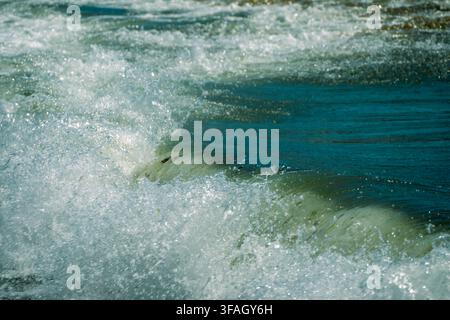 dynamic ocean waves churning into thick white sea foam as they crash and roll through deep blue water. Stock Photo