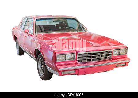 Red sedan on white background, featuring sleek design, glossy finish, prominent grille, chrome bumper, black wheels, vibrant color, minimalistic envir Stock Photo