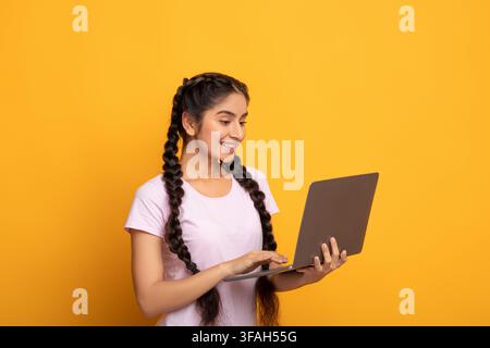 Smiling young indian lady holding and using laptop Stock Photo