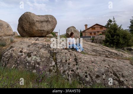 Young Woman Working Remotely on Laptop While Sitting Outdoors on Rock Stock Photo