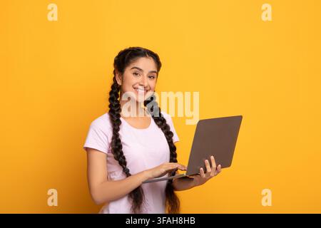 Confident young indian lady holding and using laptop Stock Photo